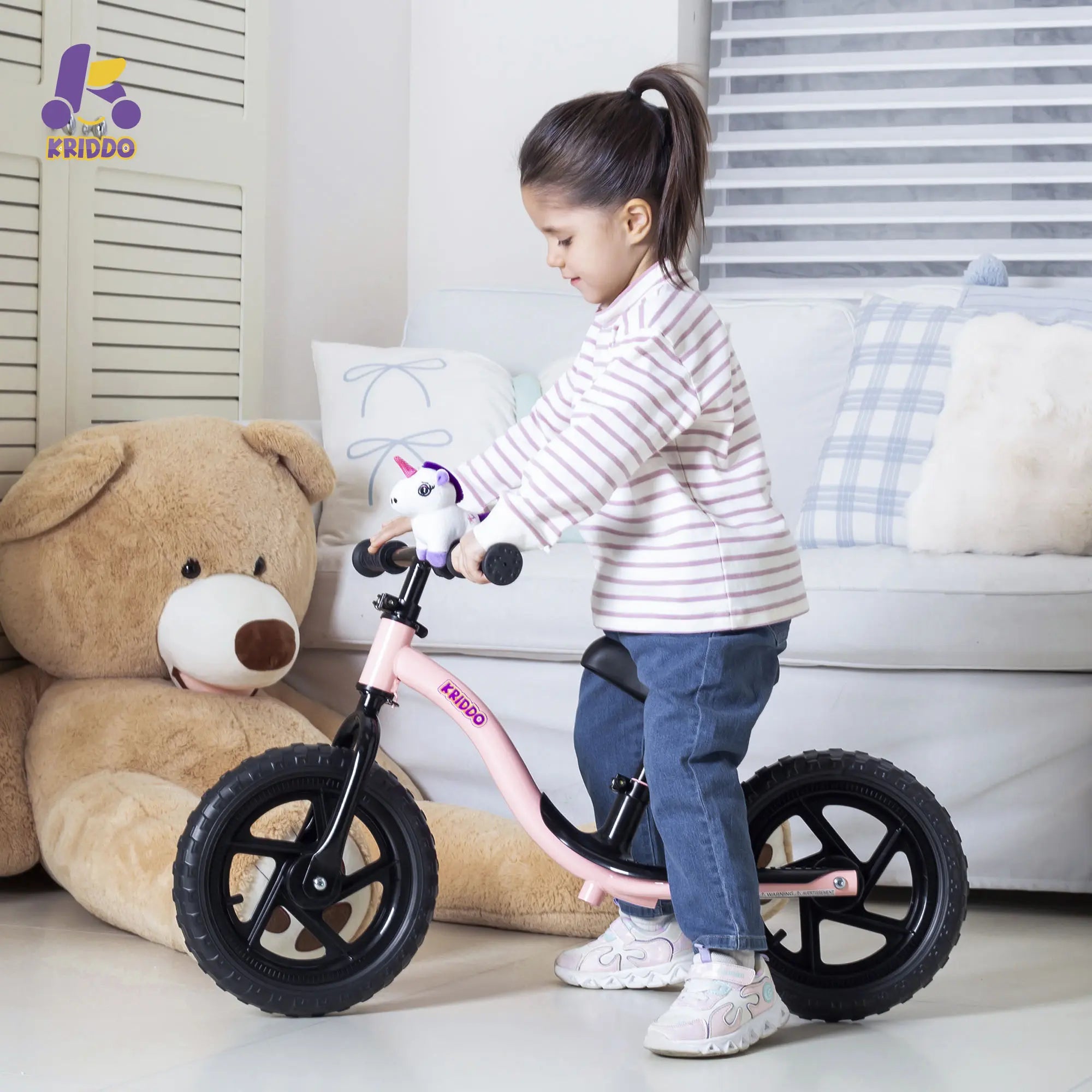 Child playing with KRIDDO balance bike with cute unicorn toy in a living room