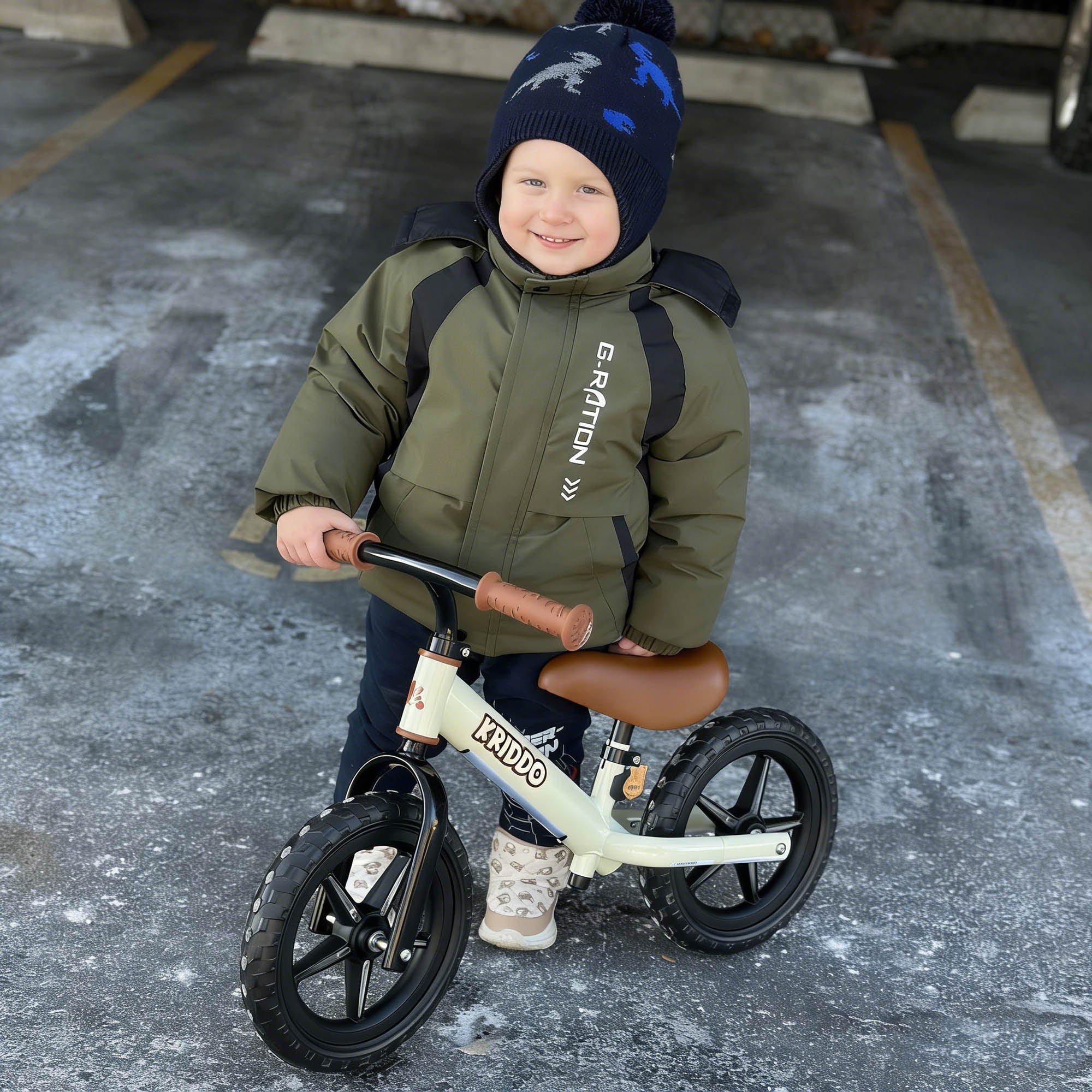 Child in a green jacket and black hat riding KRIDDO light up balance bike