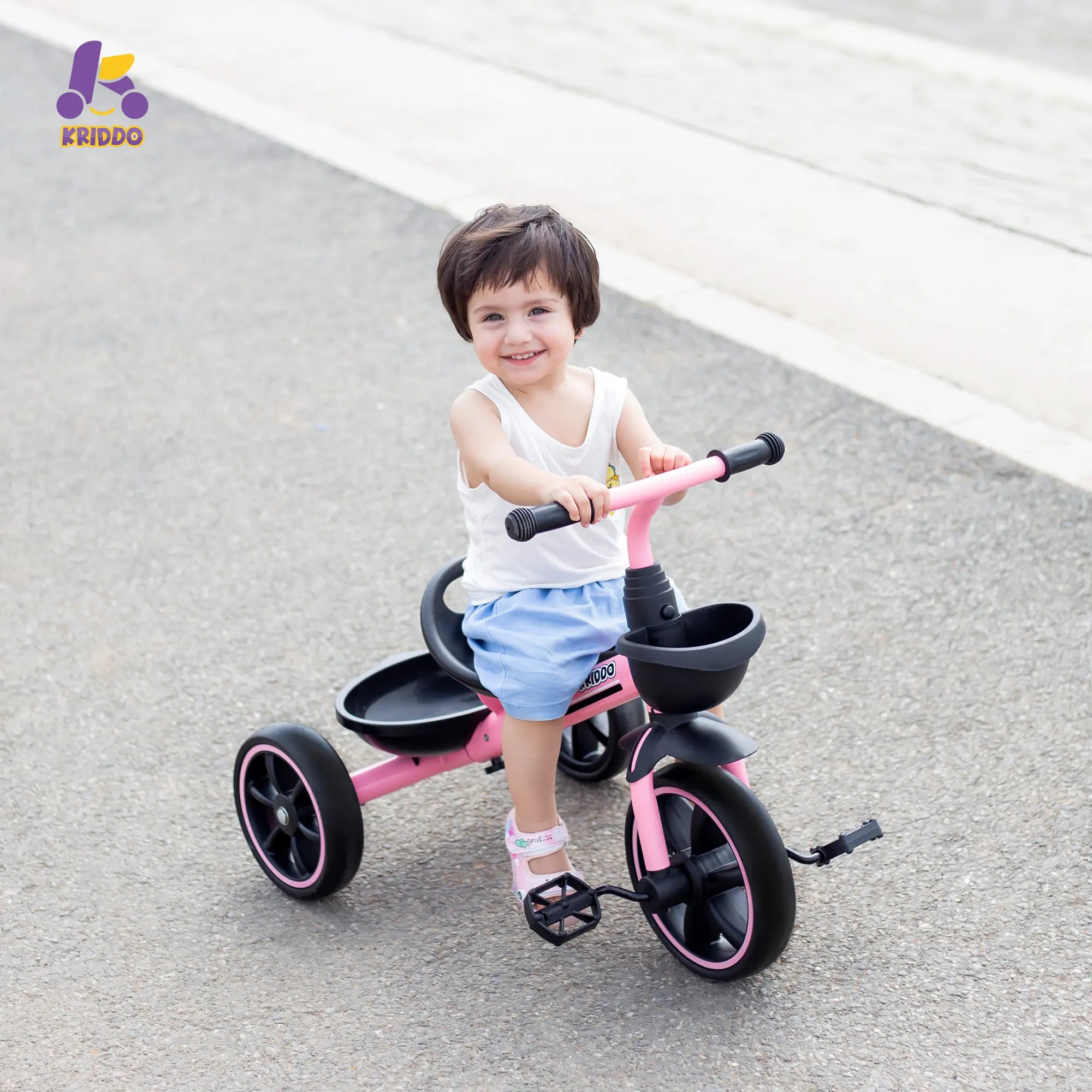 Little girl riding KRIDDO pink tricycle on a road
