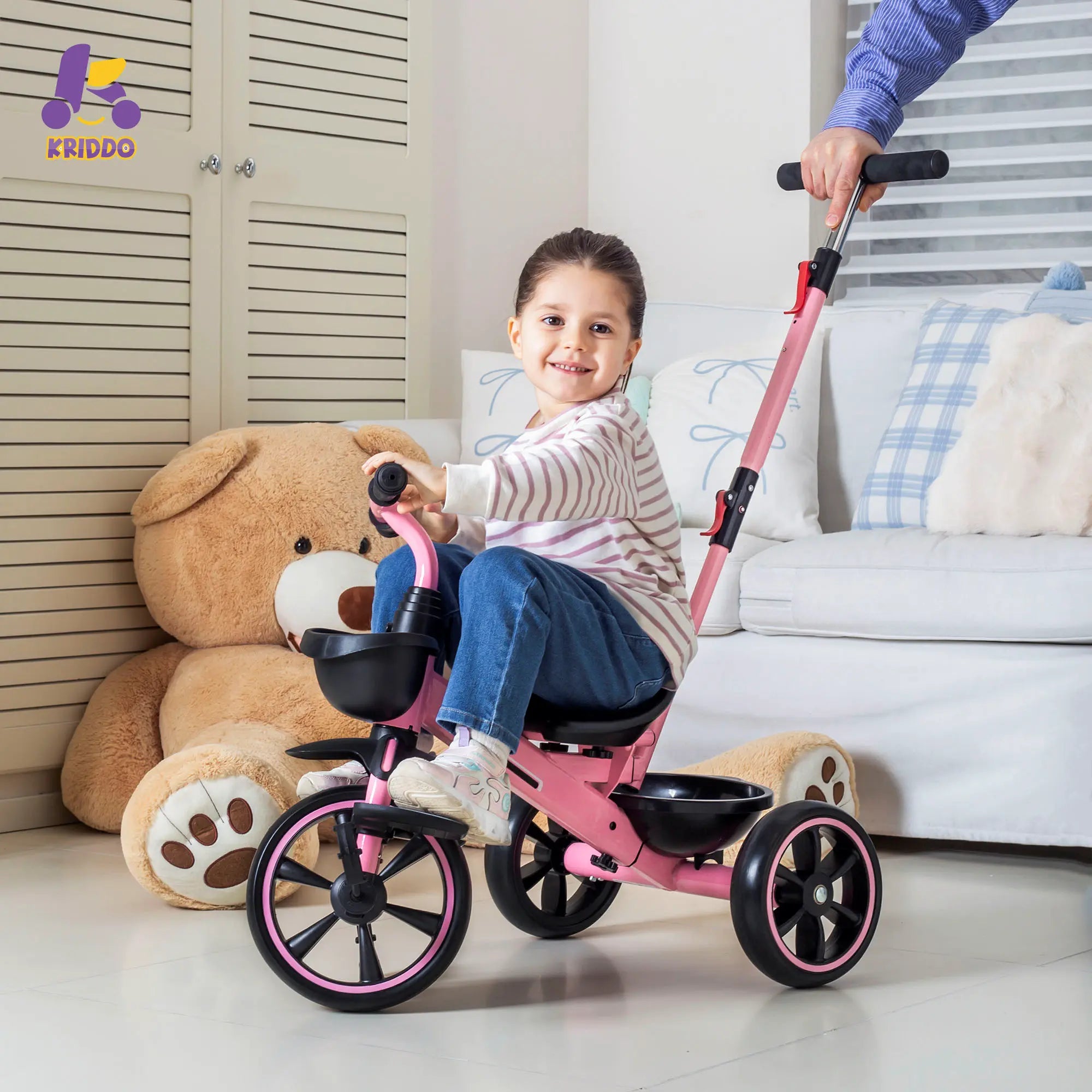 Dad pushing his daughter in a pink trike with a teddy bear near by