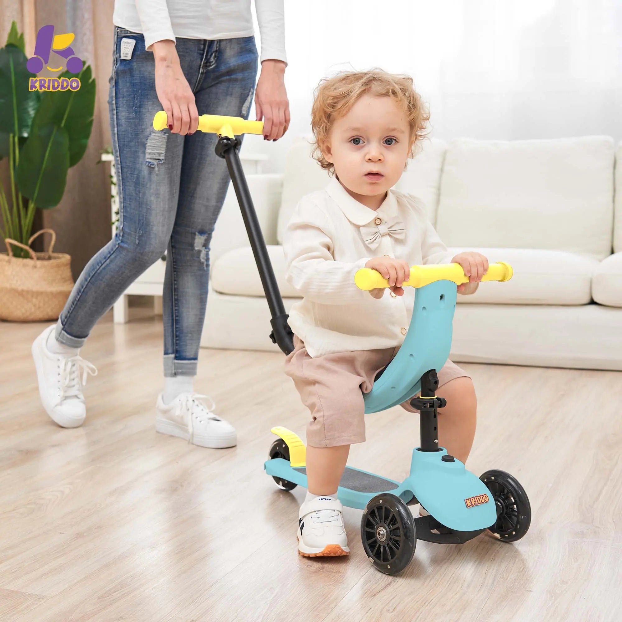 Child using a blue scooter with a yellow handlebar, accompanied by an adult