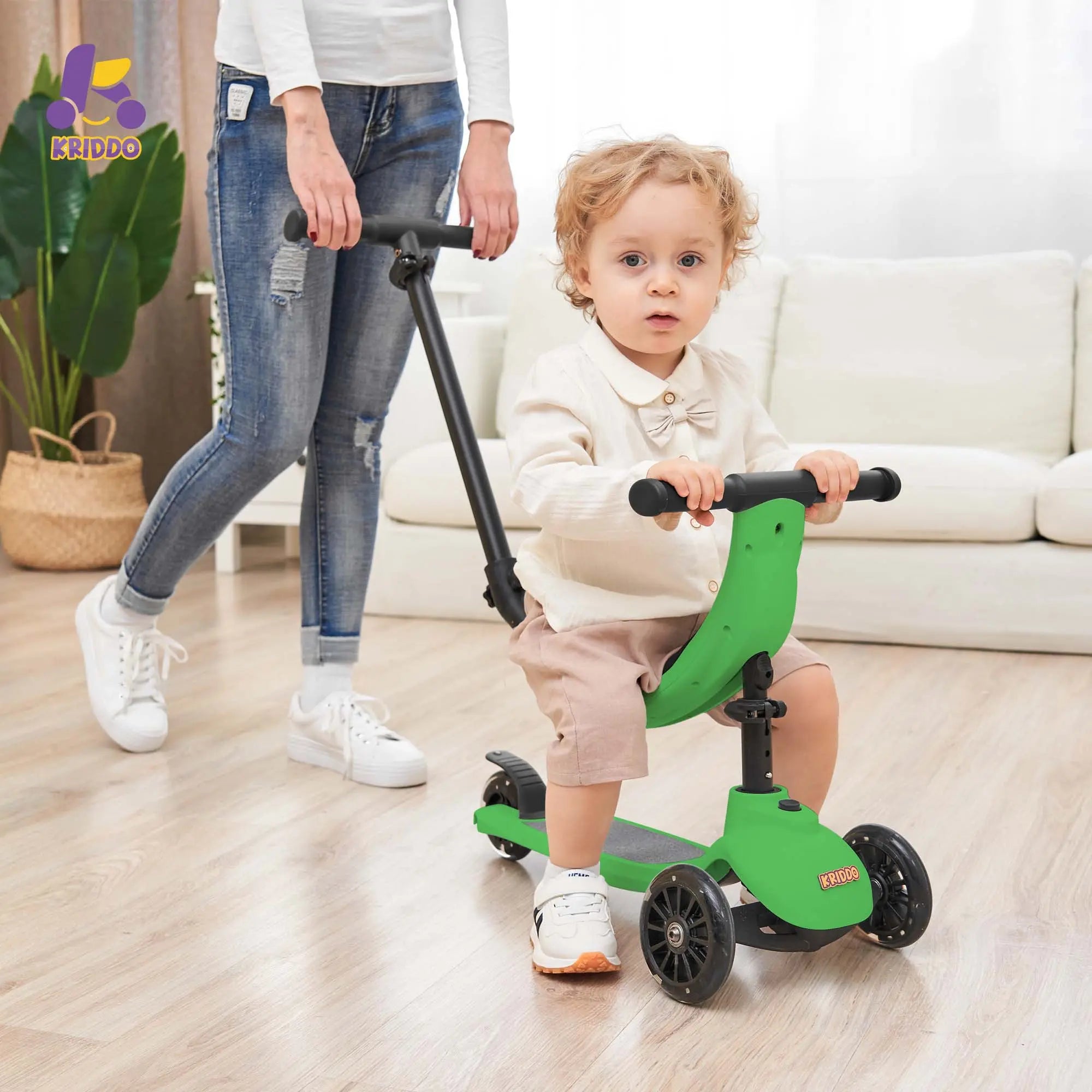 Child using a green scooter with a yellow handlebar, accompanied by an adult