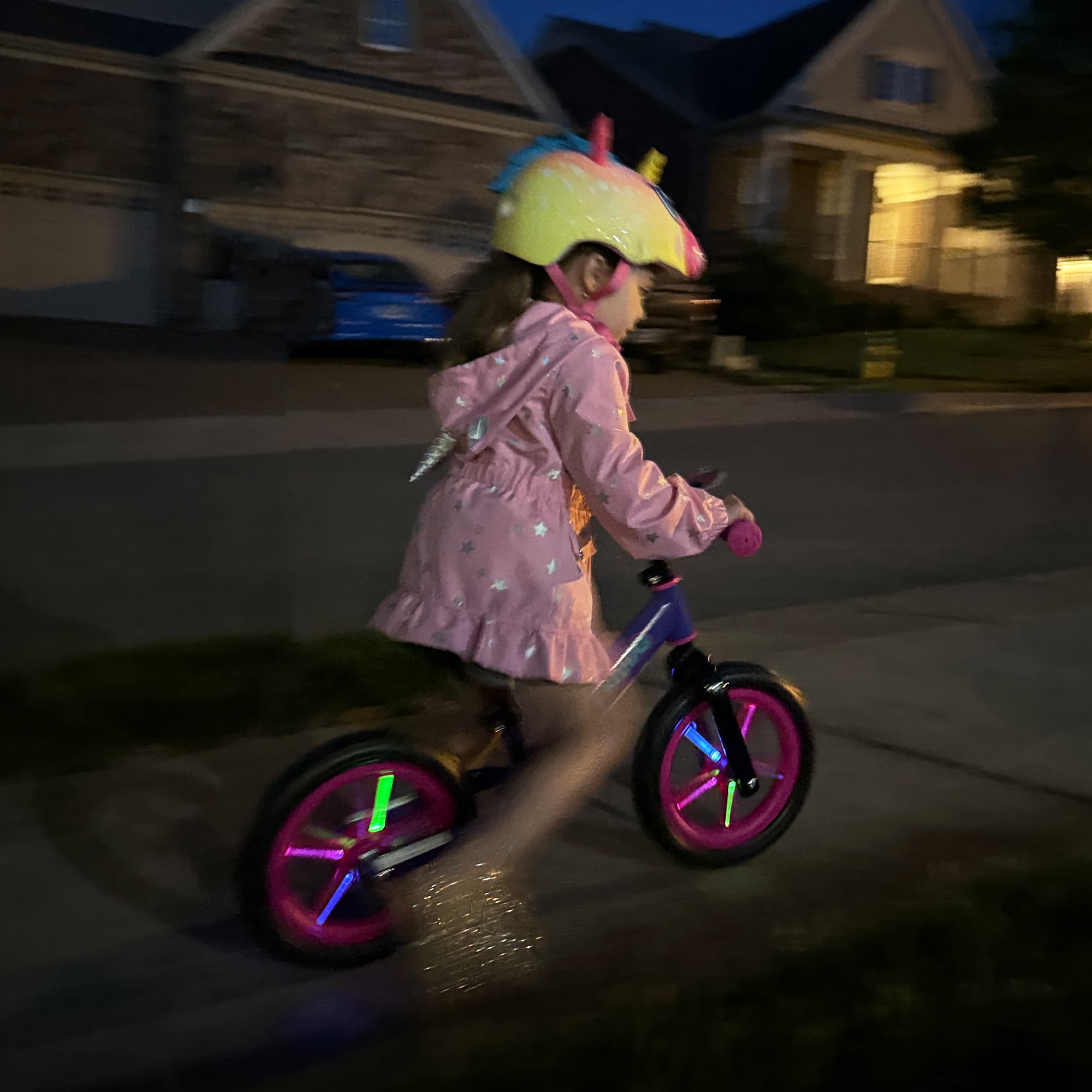 Girl riding KRIDDO balance bike with light up wheels at night in a residential area