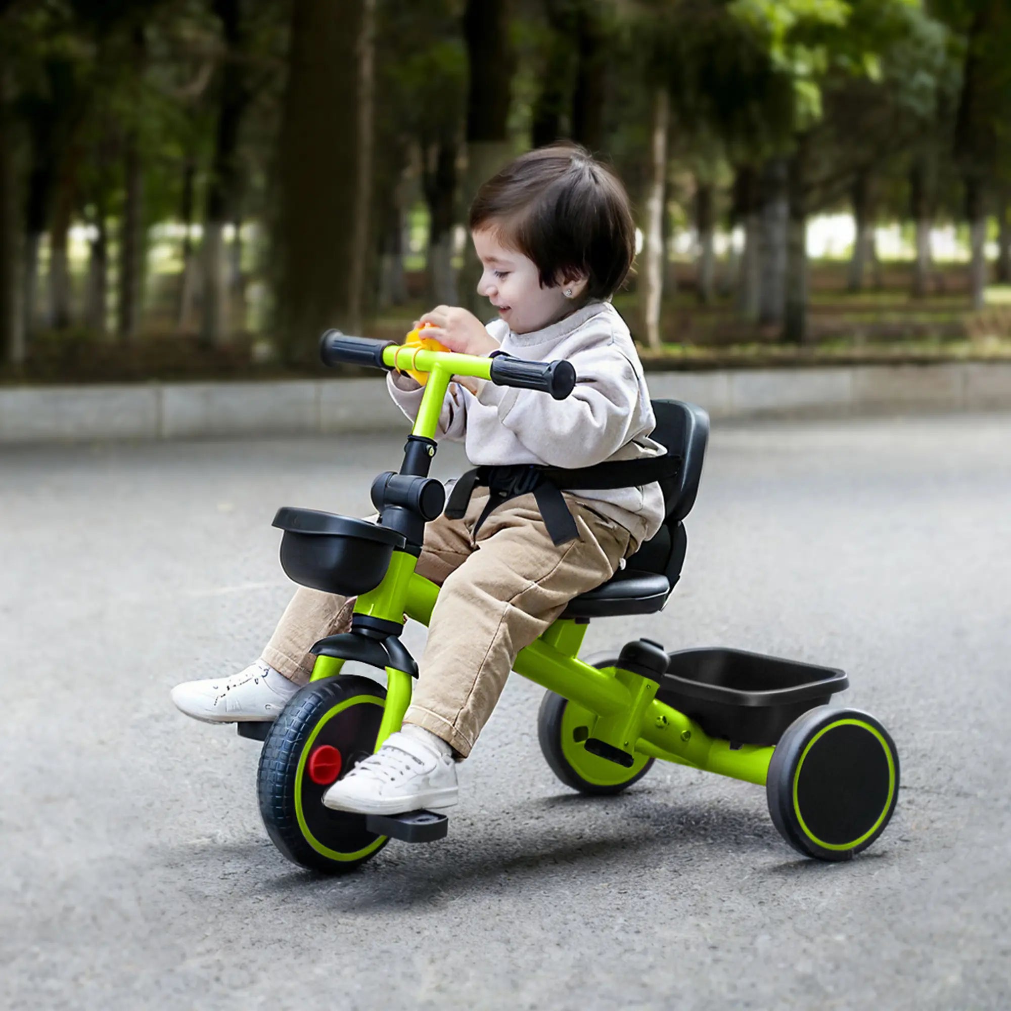 Toddler riding a green tricycle in an outdoor setting