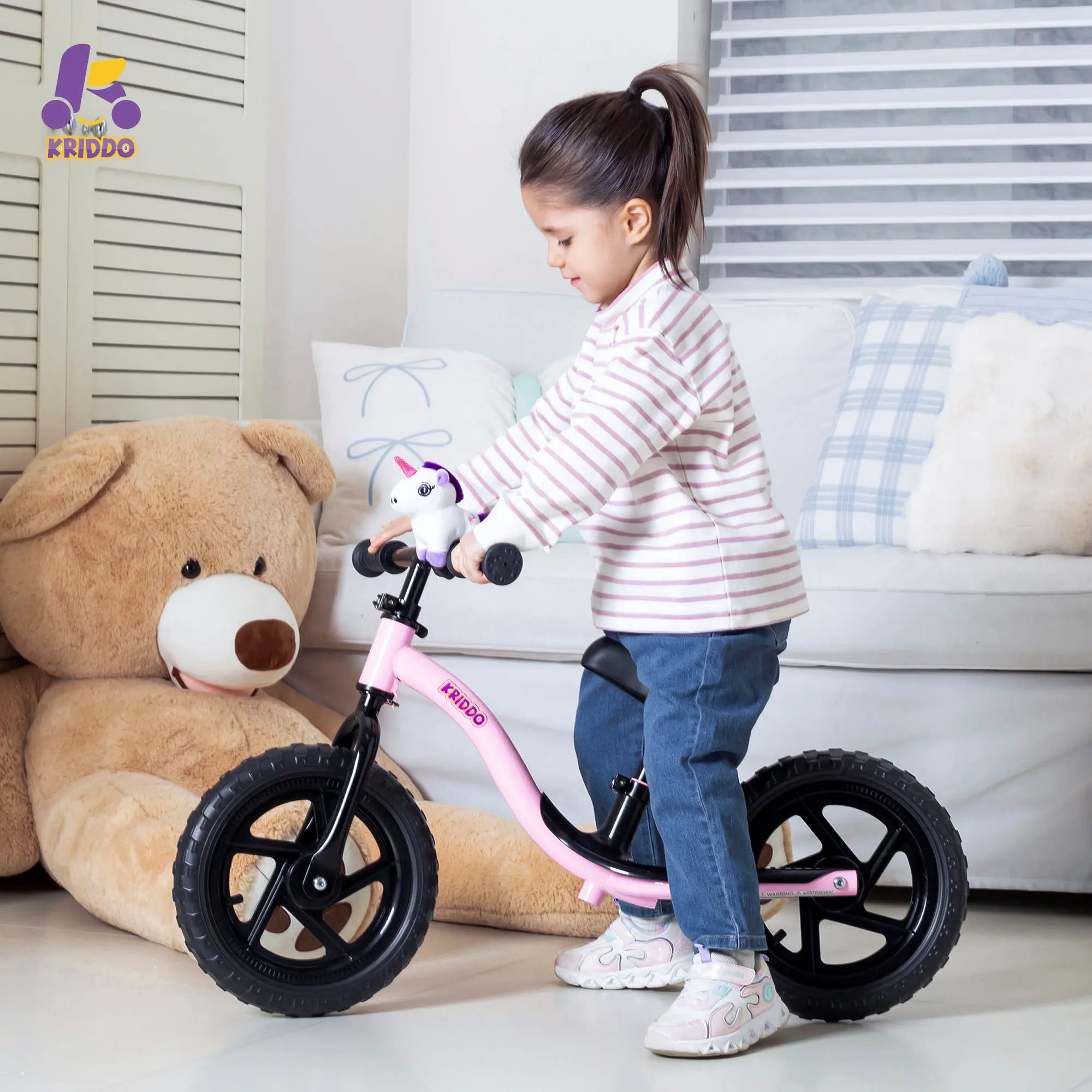 Child playing with a KRIDDO purple unicorn balance bike in a living