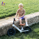 Child sitting on a stone ledge with a KRIDDO balance bike outdoors