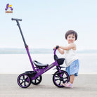Little girl with a purple push tricycle on a beach 
