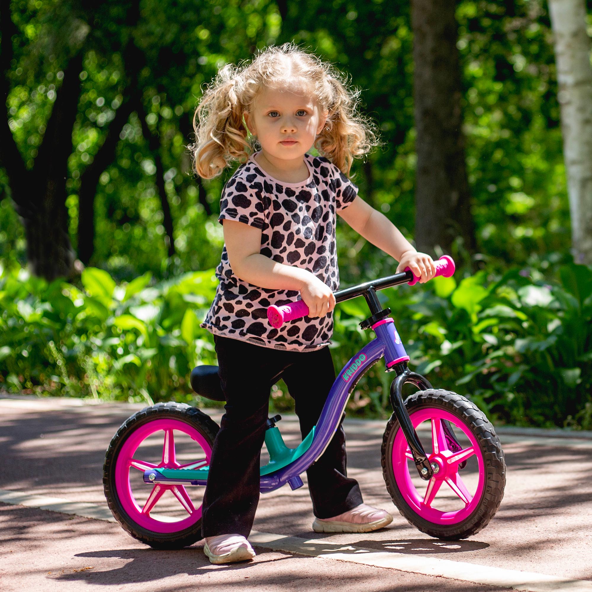 Child on KRIDDO balance bike with glowing wheels in a park