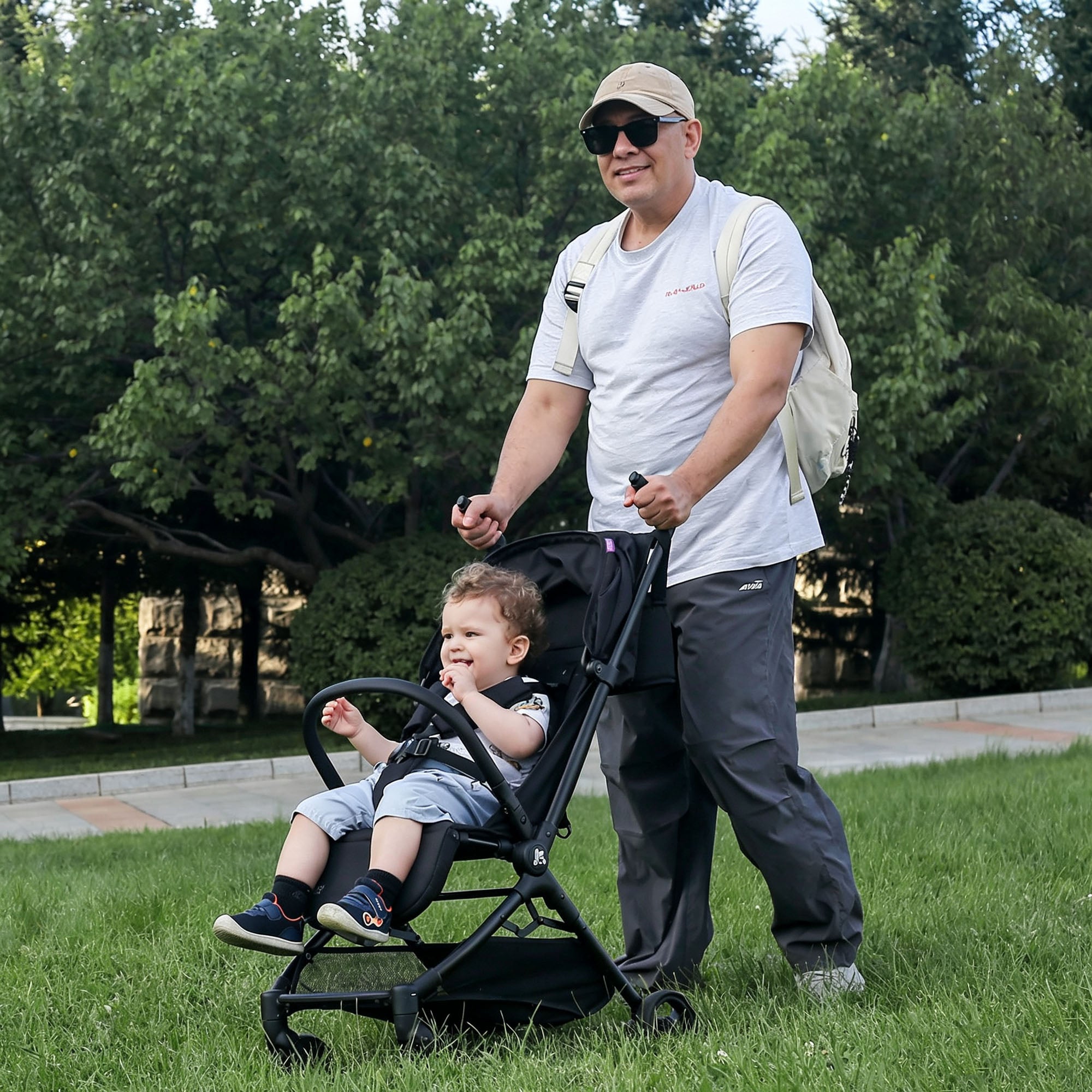 Dad pushes KRIDDO lightweight stroller with a young child sitting inside