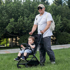 Dad pushes KRIDDO lightweight stroller with a young child sitting inside