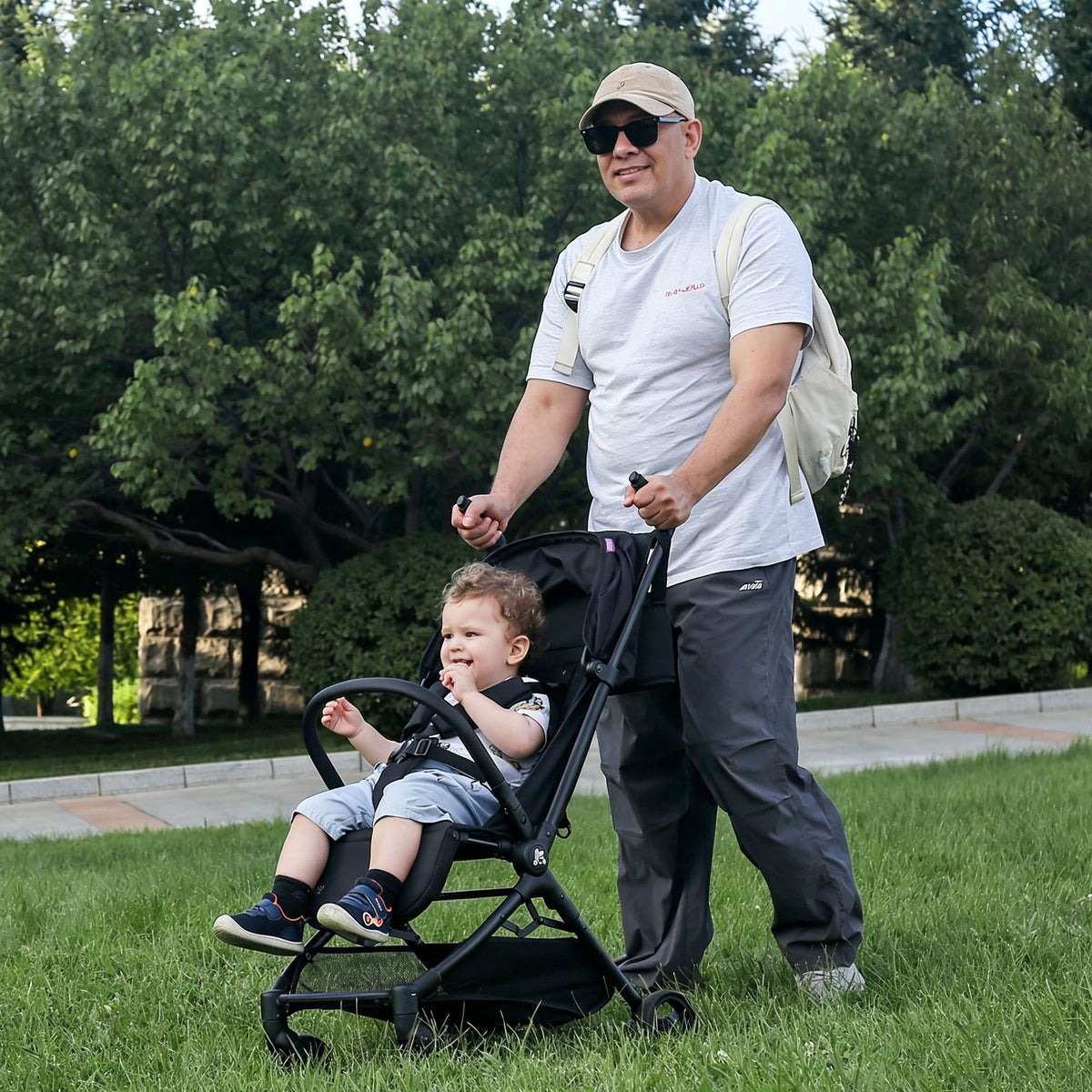 Dad pushes KRIDDO lightweight stroller with a young child sitting inside